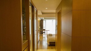 A hotel hallway leading to a bedroom with a bed, a desk, and a chair. - Guangzhou Yiyuan Apartment (Guangzhou)
