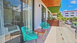 A modern balcony with glass doors, two turquoise chairs, and a small table. - MOMA Luxury condo Playa del Carmen (Playa del Carmen)