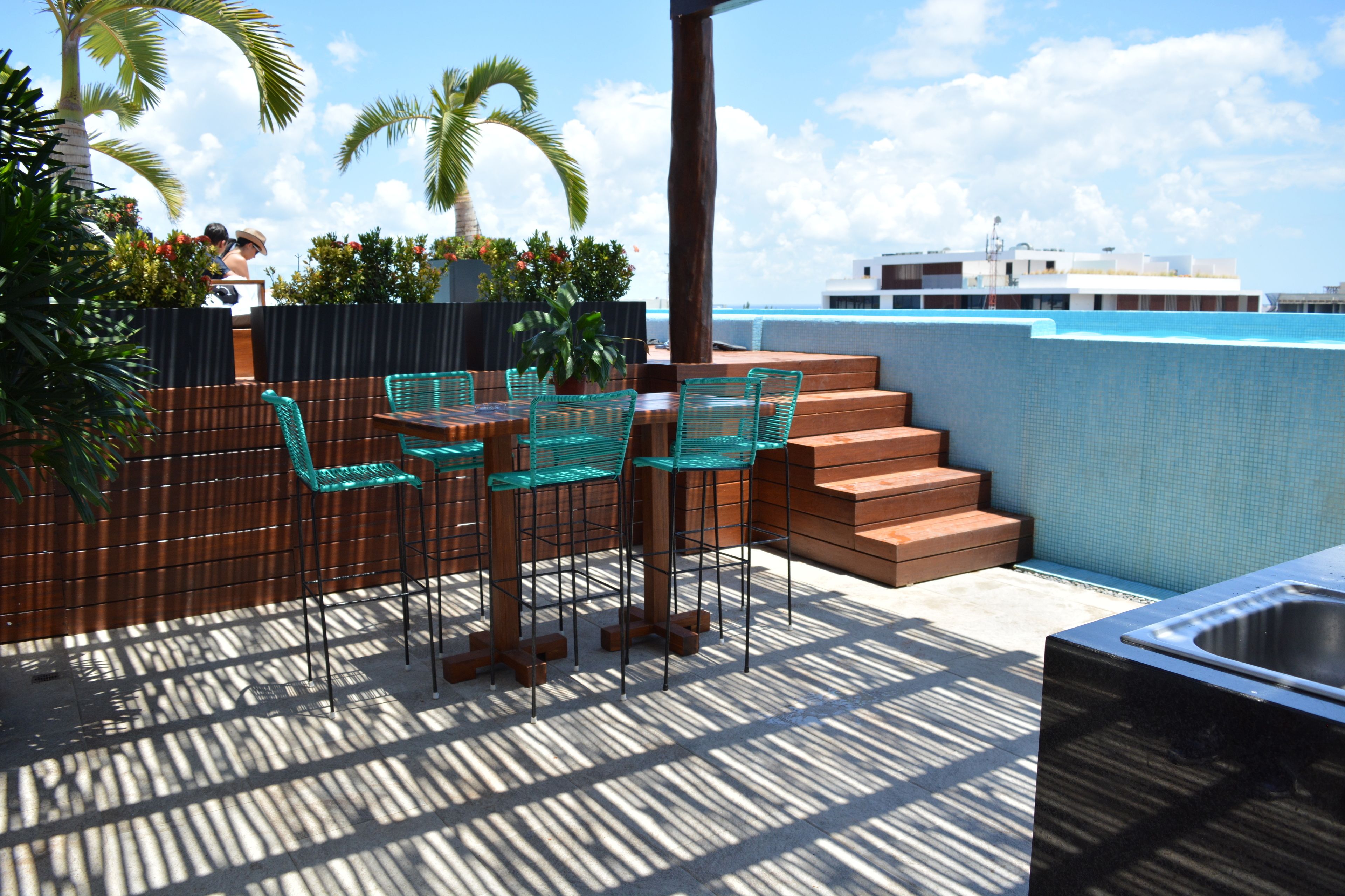A rooftop terrace with outdoor seating, a pool, and a view of the city skyline.