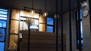 A modern interior with a wooden bench, pendant lights, and a visible clock. - Luck Esan Loft - Hostel (Ubon Ratchathani)