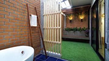 A bathroom with a white bathtub, a wooden ladder, and a white partition.