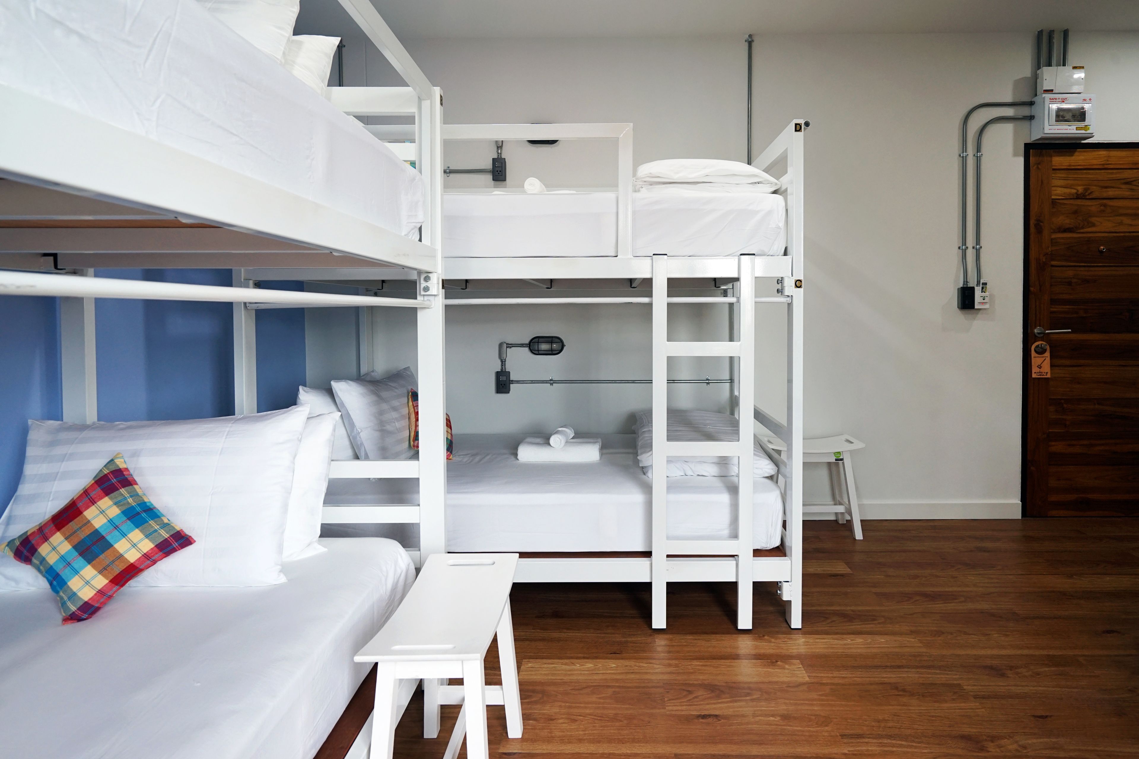 Ein Schlafsaalzimmer mit Etagenbetten, einem Schreibtisch, einer Lampe und einer Holztür.