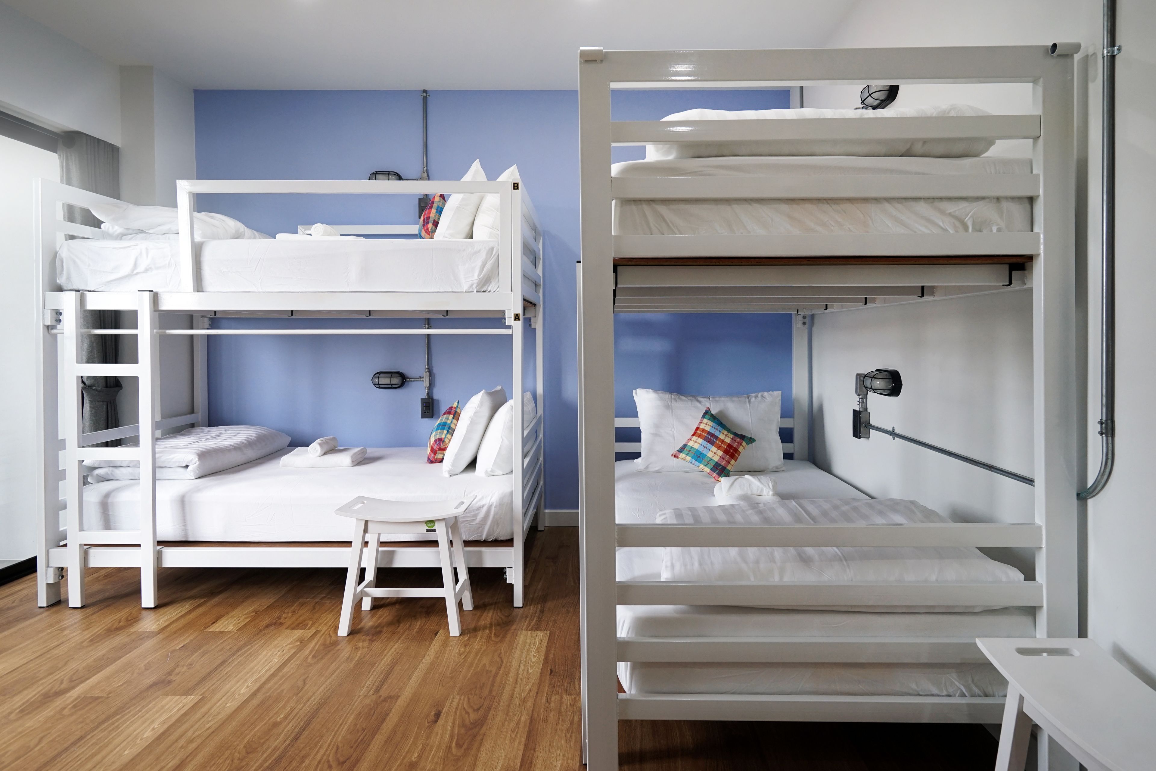 A room with two bunk beds, a small table, and a chair.