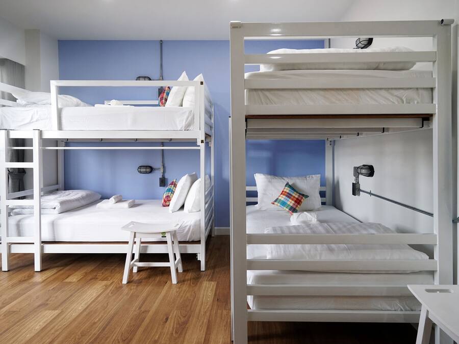 A room with two bunk beds, a small table, and a chair.