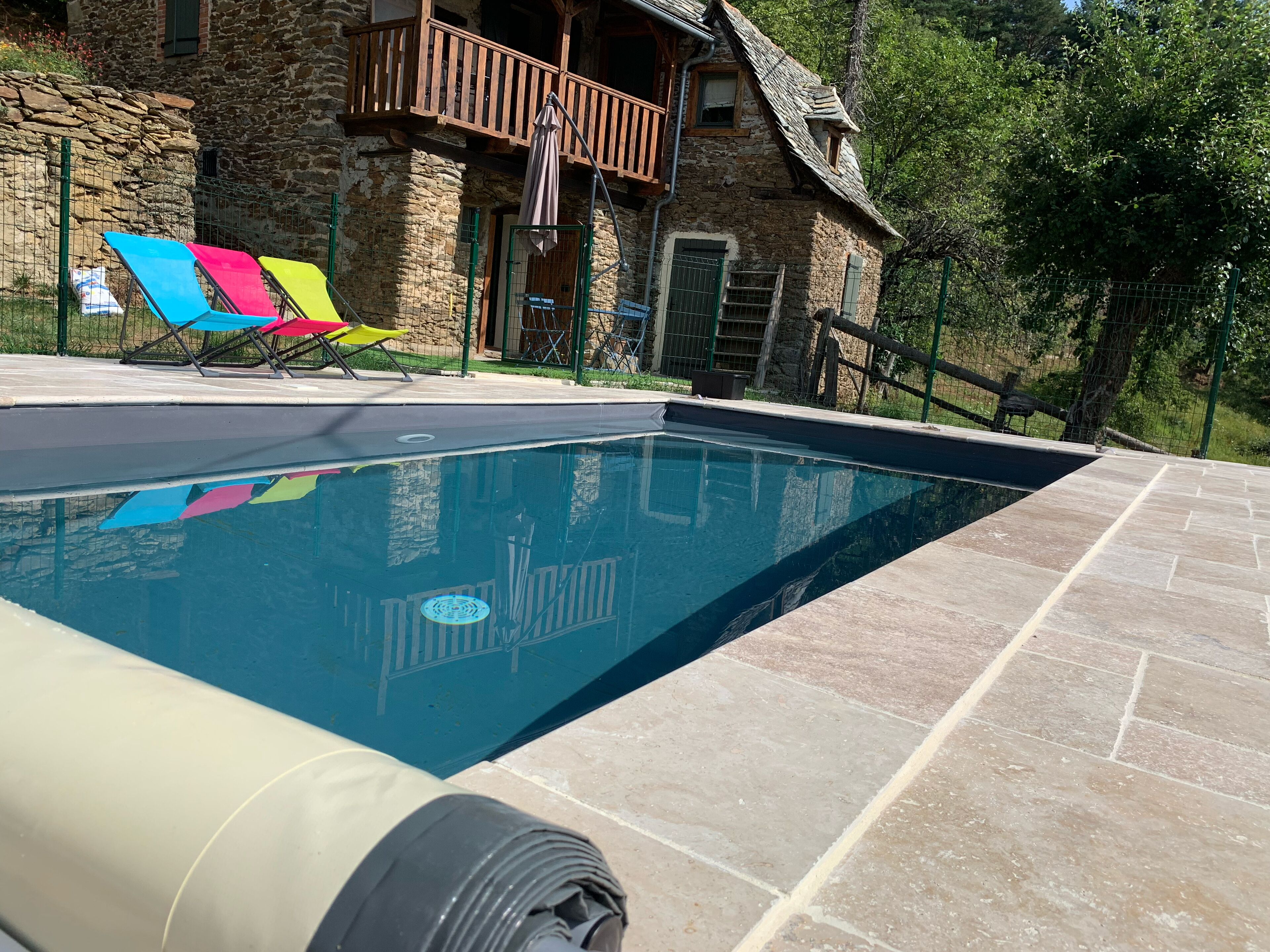 Una piscina con una casa de piedra al fondo.