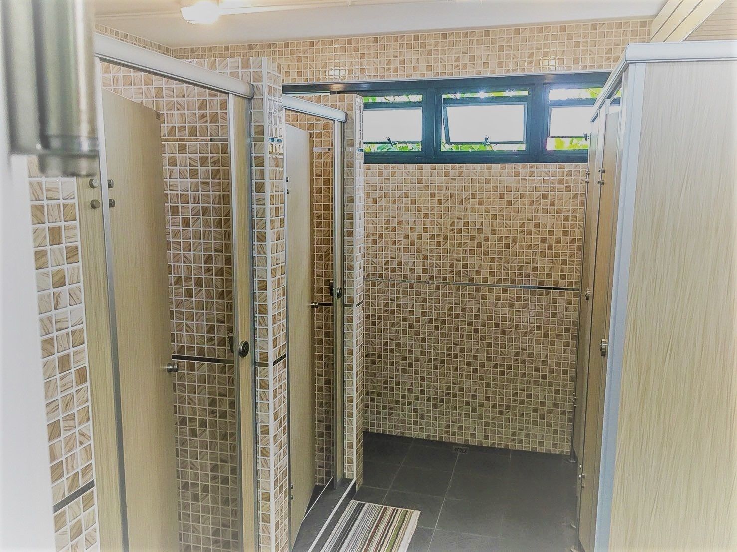 Ein Duschbereich mit Glastüren und einer gefliesten Wand.
