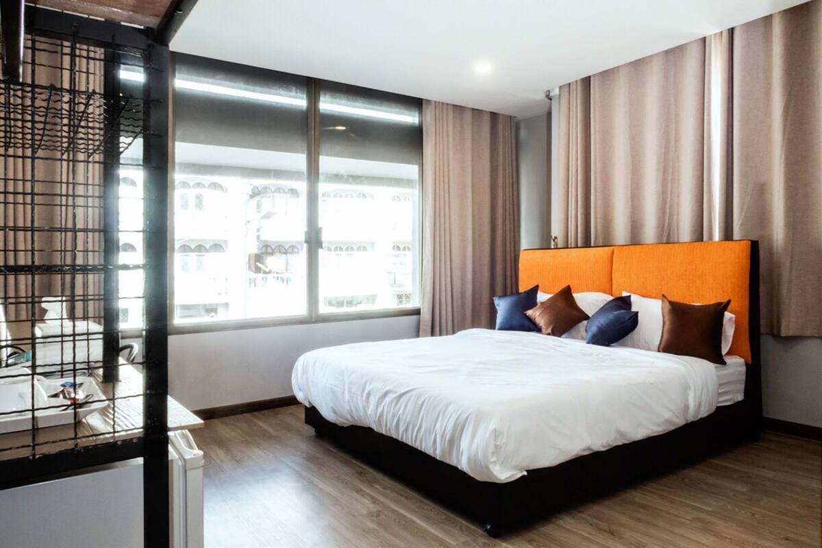 Een moderne hotelkamer met een groot bed, een bureau met stoel en een raam met gordijnen.