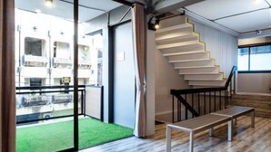 Ein modernes Interieur mit Treppe, einer Bank und Blick auf ein Gebäude mit Balkonen.