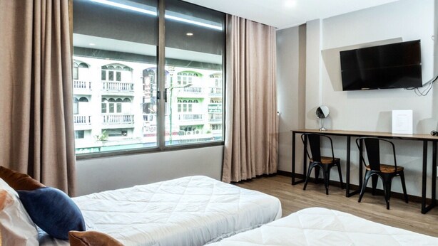 Ein Hotelzimmer mit zwei Betten, einem Schreibtisch, einem Stuhl und einem Fernseher.