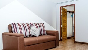 Ein braunes Ledersofa mit gestreiften Kissen in einem Raum mit Holzboden und weißer Wand.
