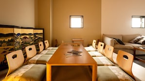 Una sala conferenze con un lungo tavolo, sedie, un divano e un tappetino in tatami.