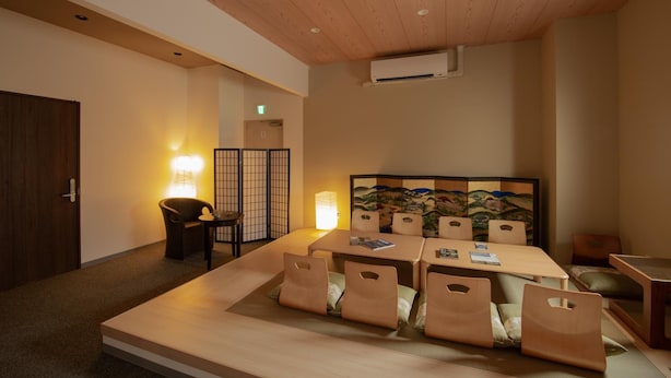 Una camera d'albergo con un letto grande, un tavolo da pranzo e un paravento tradizionale giapponese.