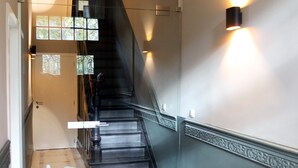 A staircase with a black railing, a wall-mounted light, and a patterned carpet.