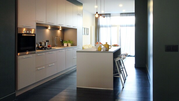 A modern kitchen with white cabinets, stainless steel appliances, and pendant lighting.
