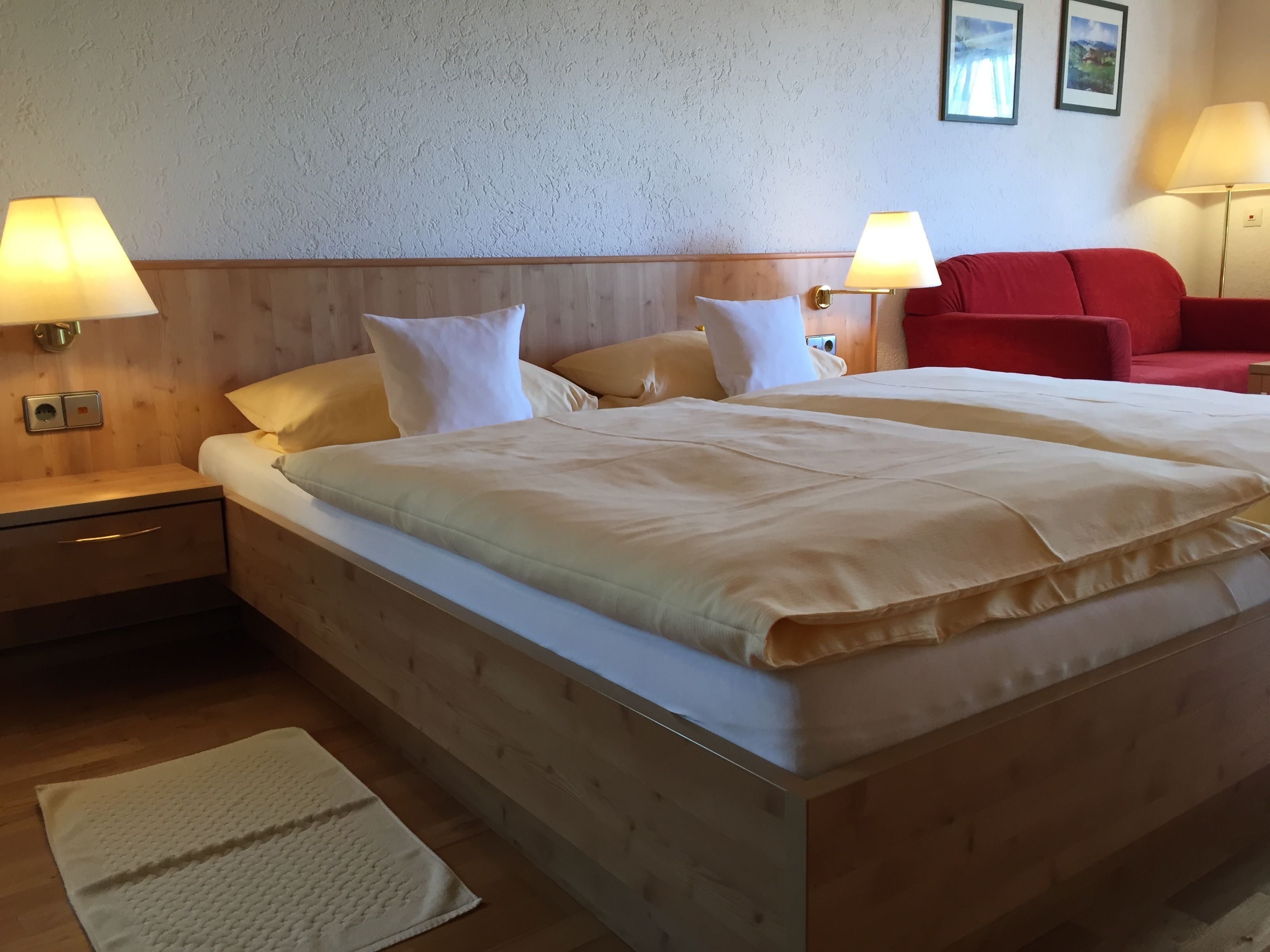 Ein Hotelzimmer mit einem großen Bett, zwei Nachttischlampen, einem roten Sofa und einem kleinen Tisch.