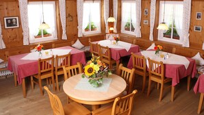 Un comedor acogedor con mesas y sillas de madera, cubiertas con manteles rosas y adornadas con centros de mesa florales.