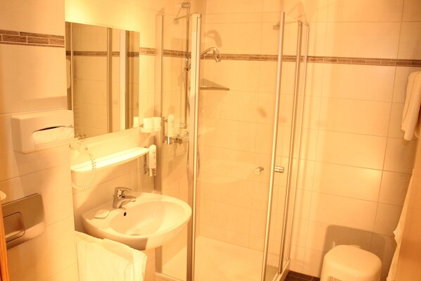A bathroom with a glass-enclosed shower, a sink, and a mirror.
