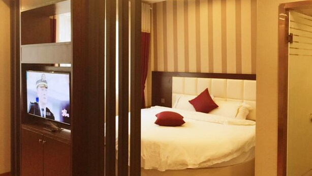 A hotel room with a curved bed, a television on a cabinet, and a striped wall. - Zhu Ying Art Hotel (Guangzhou)