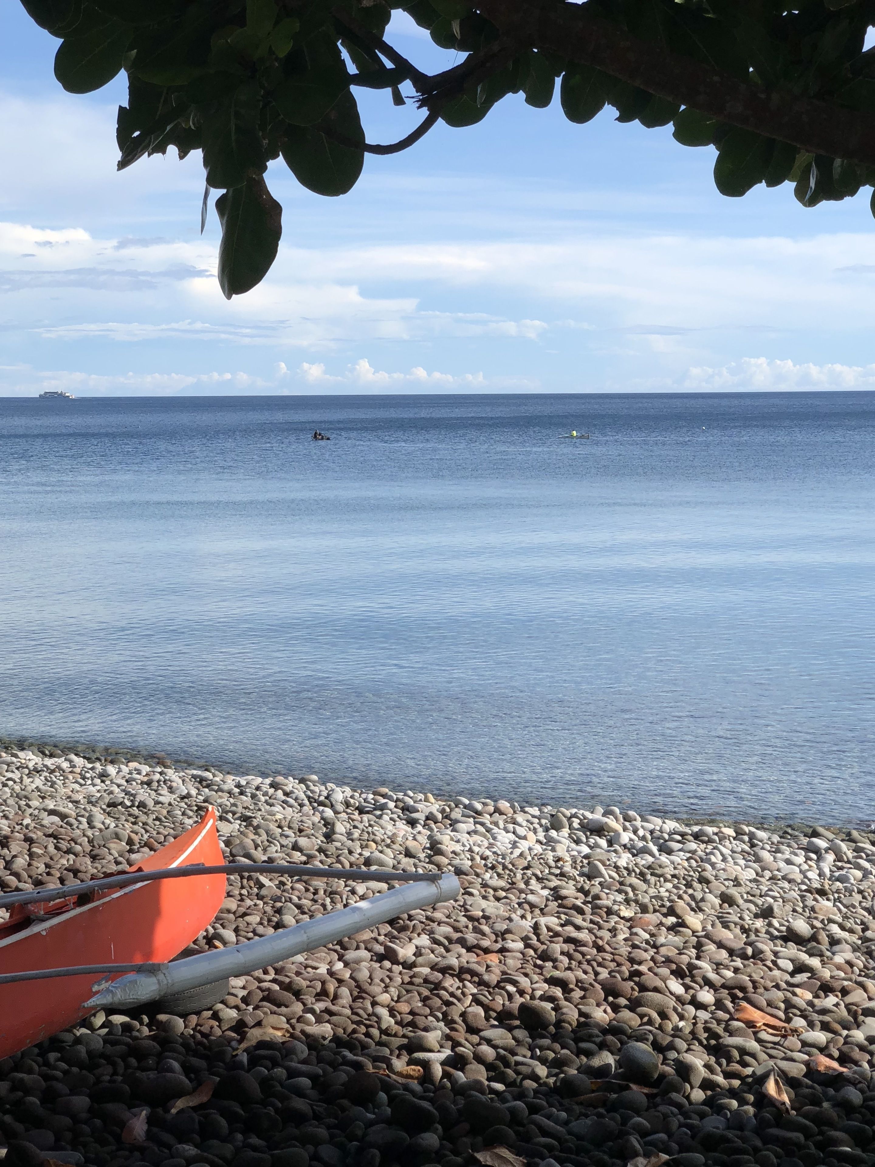 Una playa de guijarros con una fila de barcos y una vista despejada del mar.