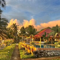Un resort con piscina, palmeras y un edificio de techo rojo.