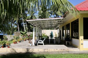 Un espacio al aire libre cubierto con plantas en macetas, una silla blanca y una mesa.
