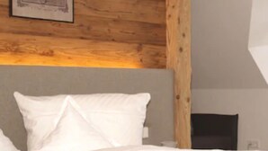 Ein Schlafzimmer mit Holzboden, einem Bett mit weißer Bettwäsche und einem gerahmten Bild an der Wand.