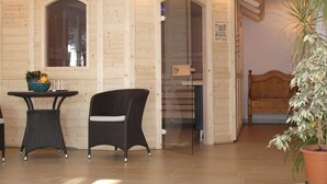 Ein Zimmer mit Holzboden, einem Korbsessel, einem kleinen Tisch mit Obstschale und einer Zimmerpflanze.