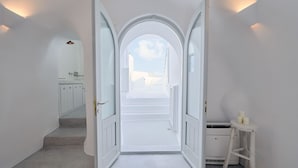 Un pasillo con paredes blancas y puertas que dan a un balcón con vistas al cielo y edificios.