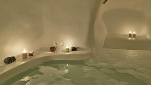 Un espacio de spa tranquilo con una bañera, velas y una copa de vino.