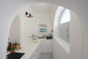 A compact kitchen with white cabinets, a coffee maker, and a toaster.