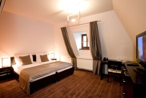 A hotel room with a bed, desk, chair, and a television. - Hotel Lahofer (Znojmo)