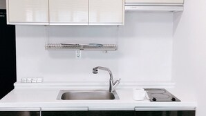 A kitchen with a stainless steel sink, a white countertop, and a built-in oven. - Leeds Pension (Seogwipo)