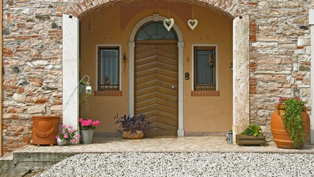 Une façade en pierre avec une porte en bois, deux fenêtres et des cœurs décoratifs au-dessus de la porte.