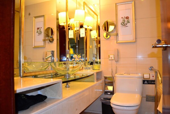 A modern bathroom with a glass bowl sink, multiple mirrors, and a toilet.