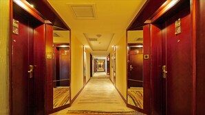 A hotel hallway with carpeted floors, wooden doors, and a long corridor leading to multiple rooms. - Enjoyable Stars Hotel Chengdu (Chengdu)