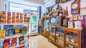 A store with shelves of snacks, a refrigerator, and a display of vintage items including a television and a clock. - Phusamor Hotel (Trang)