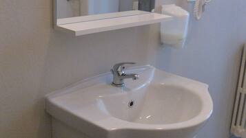 A bathroom with a white sink, a mirror, a hairdryer, and a toilet.