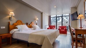 Una habitación de hotel con una cama grande, dos lámparas de noche, un televisor, un escritorio y una silla roja.