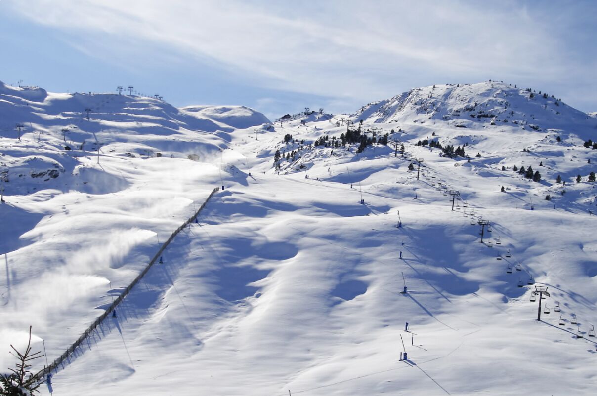 A snow-covered ski slope with ski lifts and trees.