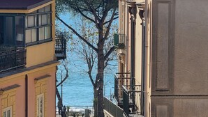 A narrow street with buildings on either side, a tree in the center, and a view of the sea in the background. - Apartment SOLE • Sapore di Mare Holidays ~ Maiori (Maiori)