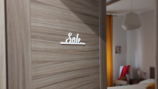 A modern bedroom with a wooden door, a bed, and a hanging light fixture. - Apartment SOLE • Sapore di Mare Holidays ~ Maiori (Maiori)