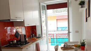A modern kitchen with white cabinets, a red pendant light, and a dining area with a table set for two. - Apartment SOLE • Sapore di Mare Holidays ~ Maiori (Maiori)