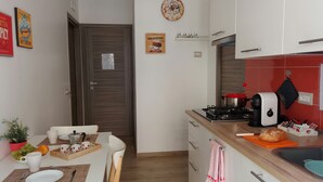 A compact kitchen with a dining area, featuring a stove, sink, and various kitchen appliances. - Apartment SOLE • Sapore di Mare Holidays ~ Maiori (Maiori)