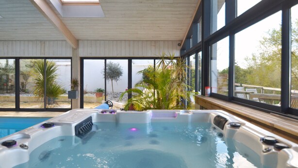 A hot tub with a view of the outdoors through large windows. - 4 star villa with sea view, islands, natural area, private heated pool, spa (Port-Des-Barques)