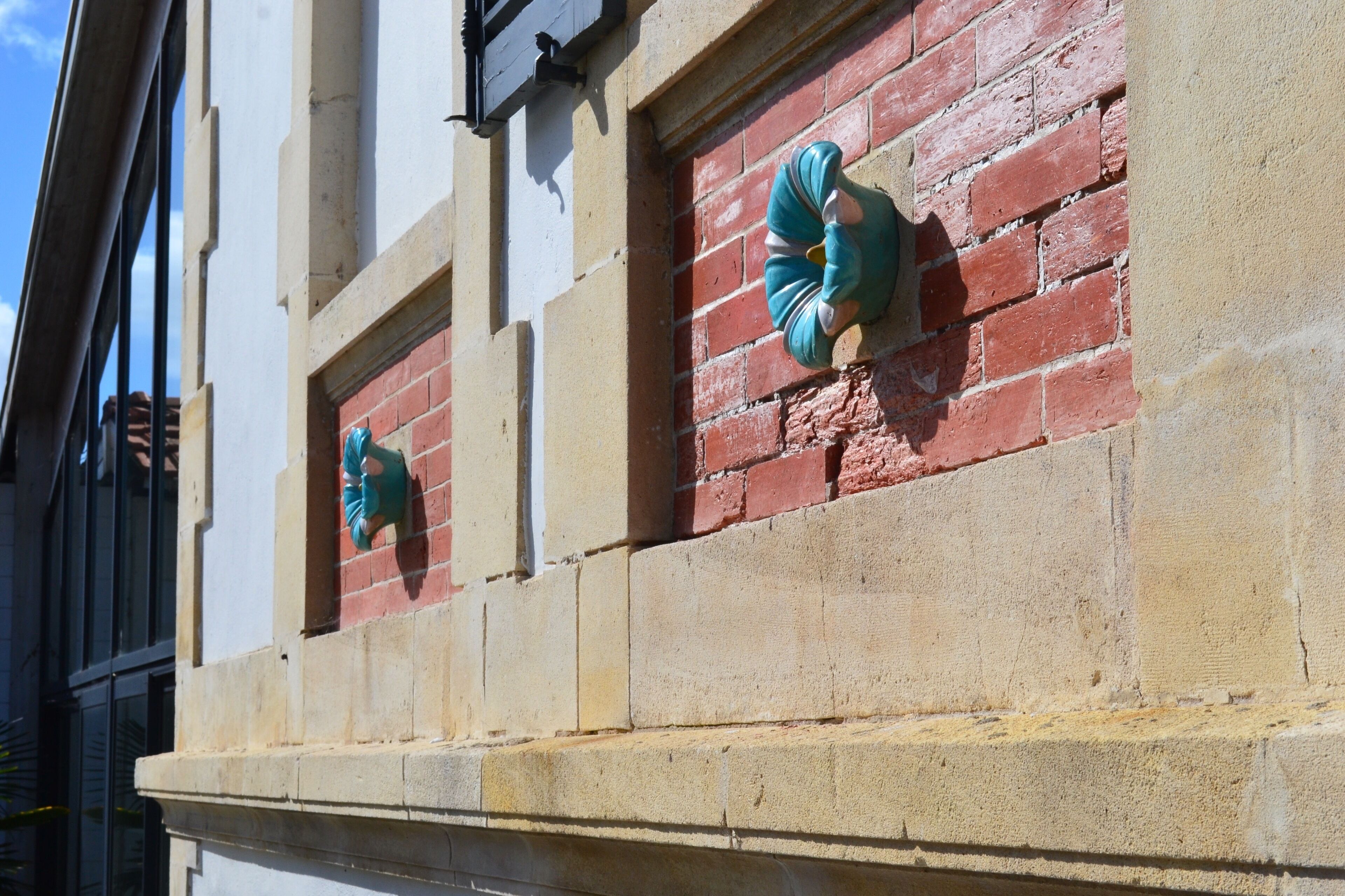 A building facade with a brick wall and two green, spiral-shaped architectural features.