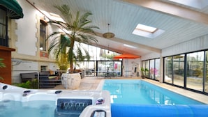 An indoor swimming pool with hot tubs, large windows, and a view of the outside. - 4 star villa with sea view, islands, natural area, private heated pool, spa (Port-Des-Barques)