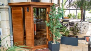 A wooden sauna with a sliding door, surrounded by potted plants and outdoor furniture. - 4 star villa with sea view, islands, natural area, private heated pool, spa (Port-Des-Barques)