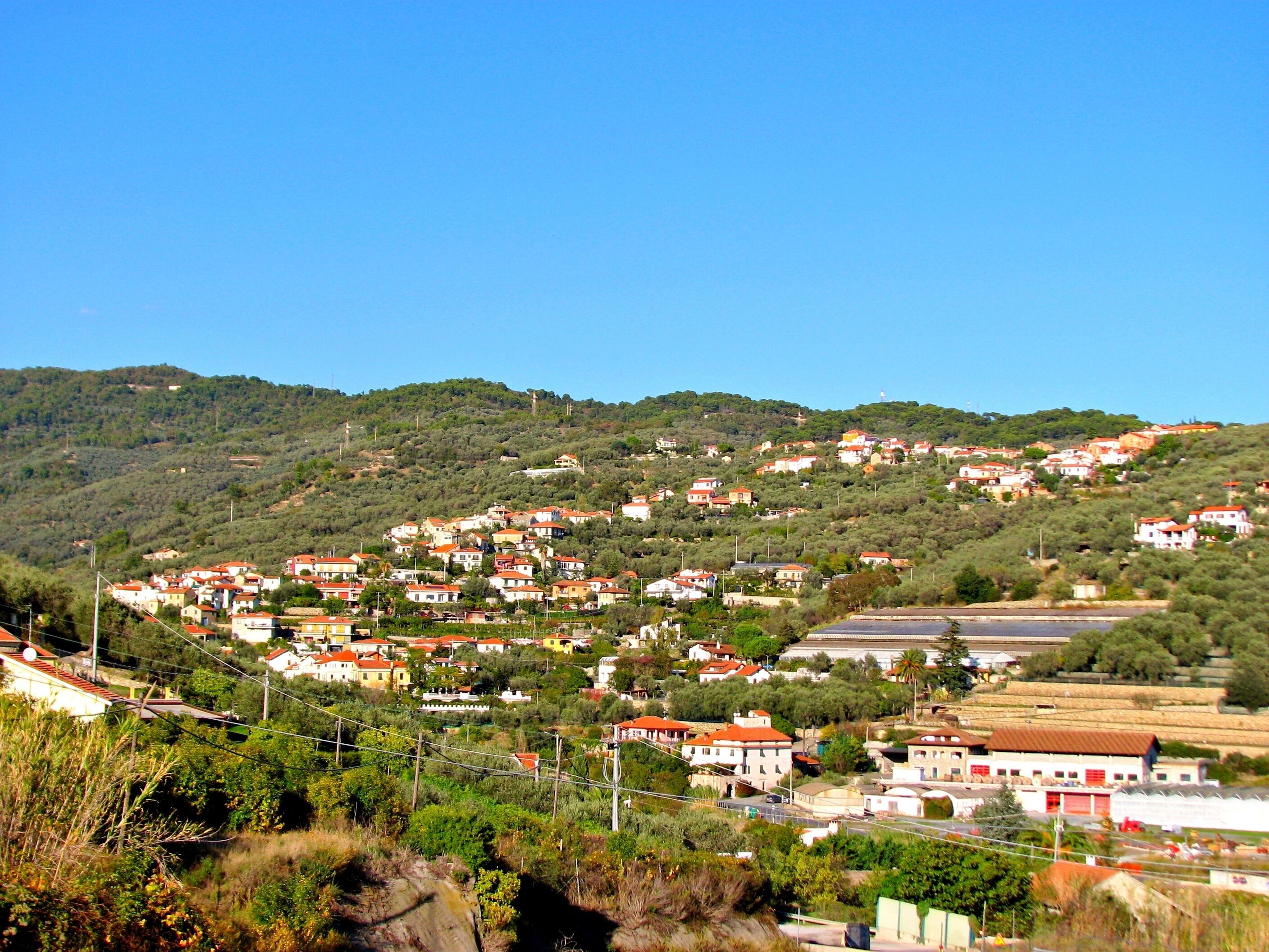 A hillside village with traditional architecture, narrow roads, and a mix of residential and commercial buildings.