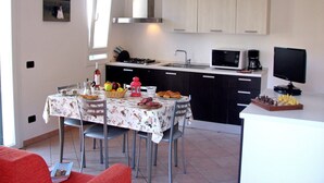 Una cocina con una mesa, sillas, estufa, fregadero y microondas.