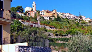 Un pueblo en la ladera de una colina con edificios, incluyendo una iglesia con campanario, y abundante vegetación.